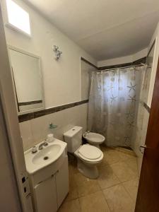 Baño blanco con aseo y lavamanos en BELLA VISTA Hostel, Aparts & Complejo de Cabañas en Santa Rosa de Calamuchita