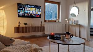een woonkamer met een tafel en een televisie bij Angerpartments-Sonnige große Wohnung mit Balkon und kostenlosen Parkplatz in Döbriach