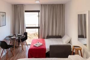 a hotel room with a bed and a table and chairs at Lindo e aconchegante apto proximo ao centro PGO309 in Poços de Caldas