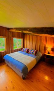 a bedroom with a bed in a room with wooden walls at La Ruka Negra in Puelo