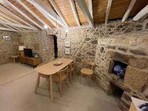 a room with a table and a stone fireplace at Casa Velha-SantiagoFamilyHouse in Sever do Vouga