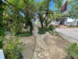 un jardín con un árbol y un camino de piedra en Villa Flores en Navalcarnero