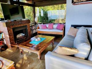 un soggiorno con divano e camino di La Roca House a Praia do Rosa