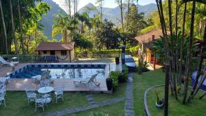 a backyard with a pool with chairs and a table at Pousada Beija Flor - Lumiar in Lumiar