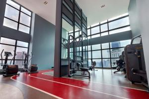 a gym with treadmills and ellipticals in a building with windows at Tribeca Serviced Hotel by Millennium in Kuala Lumpur