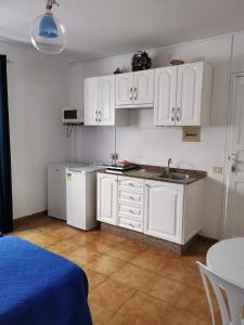 a kitchen with white cabinets and a sink and a table at Apartamentos Playamar II in Valle Gran Rey