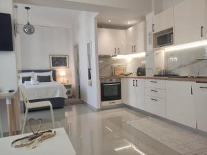 eine Küche mit weißen Schränken und ein Bett in einem Zimmer in der Unterkunft Διαμέρισμα studioJoy4stay στο Χαλάνδρι in Athen