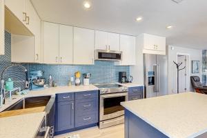 a kitchen with white cabinets and blue appliances at Purple Pelican Cottage in Marco Island