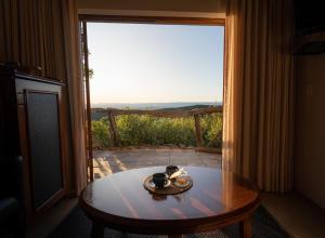 a table in front of a glass door with a view at Kuzuko Lodge in Addo