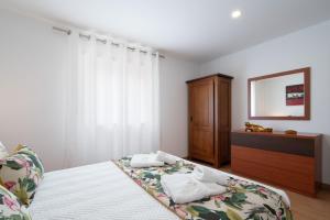 a bedroom with a bed and a dresser and a mirror at Casa Petisqueira 88-Paredes-Oporto in Rebordosa