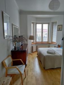 a bedroom with a bed and a chair and windows at Top-floor studio, near park & sea, great transit in Helsinki