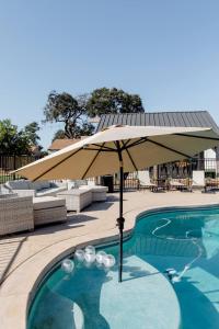 een zwembad met een parasol naast een zwembad bij Beautiful spacious guest home in Roseville
