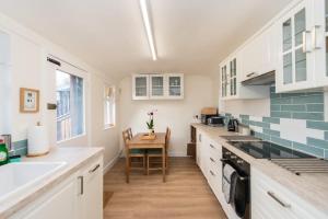 a kitchen with white cabinets and a wooden table at Stunning Stables Cottage in East Lothian Country Estate in North Berwick