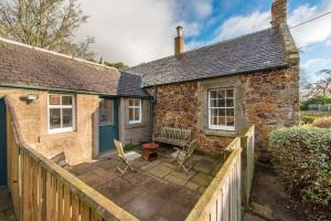 a stone cottage with a wooden fence and a patio at Stunning Stables Cottage in East Lothian Country Estate in North Berwick