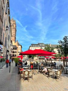 a group of people sitting at tables under red umbrellas at /Sacré studio/Parking privé/Wifi in Rodez