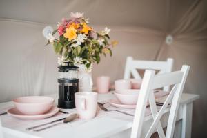 a table with pink dishes and a vase of flowers at Glamping Bobrowniczki w Kotlinie Kłodzkiej in Szczytna