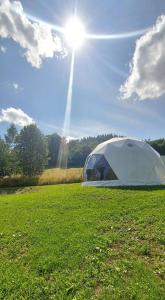 una tienda en un campo con el sol en el cielo en Glamping Bobrowniczki w Kotlinie Kłodzkiej en Szczytna