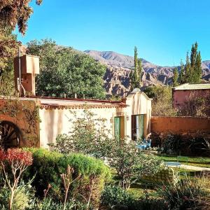 a house with a garden with mountains in the background at Los Arcabuceros Posada Boutique in Tilcara