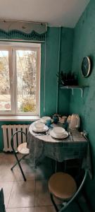 ein Raum mit einem Tisch und Stühlen und einem Fenster in der Unterkunft Двухкомнатная квартира на Арбате in Almaty