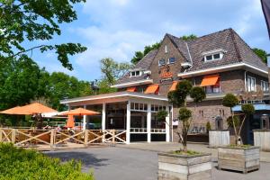 Hotel Loco في Lievelde: مطعم فيه مظلات برتقال امام المبنى