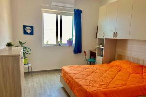 a bedroom with an orange bed and a window at Cozy appartament sea view in Marsaskala