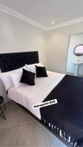 a bedroom with a large white bed with black pillows at Mphagahle B&B in Mthenti