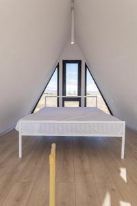 un letto bianco in una stanza con ampie finestre di Chill With Tech 