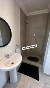a bathroom with a sink and a shower with a mirror at Mphagahle B&B in Mthenti
