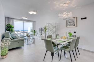 a dining room and living room with a table and chairs at Luxury apartment. Heated Pool. AC. Ocean view! in Adeje
