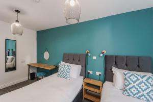 a bedroom with two beds and a blue wall at Deluxe Studio Apartments in Derby