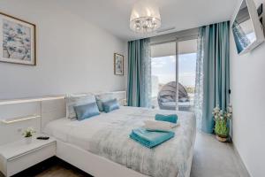 a white bedroom with a large bed with blue pillows at Luxury apartment. Heated Pool. AC. Ocean view! in Adeje +14 photos