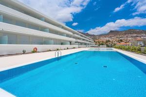 a swimming pool in front of a building at Luxury apartment. Heated Pool. AC. Ocean view! in Adeje