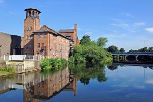 an old brick building next to a river at Deluxe Studio Apartments in Derby