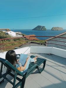 a girl sitting on a chair with a laptop at Casa da Canada da Fajã in Feteira