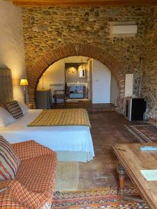 - une chambre avec un grand lit et un mur en pierre dans l'établissement Can Carbó de Peralada, à Peralada