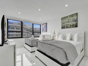 een witte slaapkamer met 2 bedden en een groot raam bij Ocean View Retreat Beach Service 1603 in Miami Beach