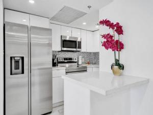 een witte keuken met een koelkast en een vaas met bloemen bij Ocean View Retreat Beach Service 1603 in Miami Beach