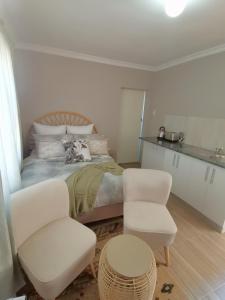 a bedroom with a bed and two white chairs at Izibusiso Guest room in East London