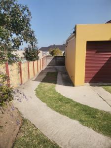 a sidewalk next to a building with a garage at Izibusiso Guest room in East London