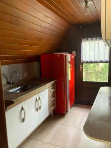 uma cozinha com um frigorífico vermelho e um lavatório em Chalé amor perfeito em Campos do Jordão
