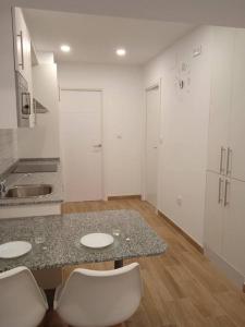 a kitchen with a table and two white chairs at La casa del Timón.Planta baja in Muros