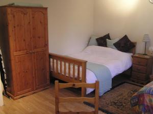 a bedroom with a bed and a wooden cabinet at Chimneys B&B in Ipswich