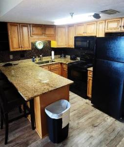 a kitchen with wooden cabinets and a black refrigerator at Condo Daytona Beach in Daytona Beach Shores