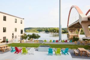 a group of colorful chairs and tables on a patio with a bridge at The Confluence Hotel in Hastings