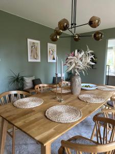 una mesa de comedor de madera con sillas y un jarrón con flores en Prästgården en Norberg