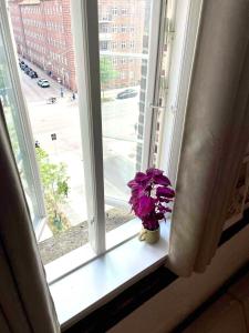 a vase with purple flowers sitting on a window sill at Charming Loft City Center in Copenhagen