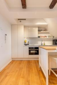 a kitchen with white cabinets and a wooden floor at Charming Loft City Center in Copenhagen