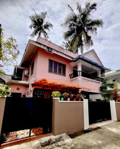 una casa rosa con una valla negra delante de ella en OCEAN PEARL RESIDENCY, en Kochi