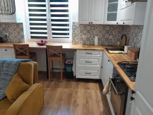 a kitchen with white cabinets and a wooden counter top at Apartament "Konie i anioły" in Boguszów-Gorce