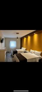 Habitación de hotel con 2 camas y pared amarilla en Hotel Real Briseñas, en La Barca